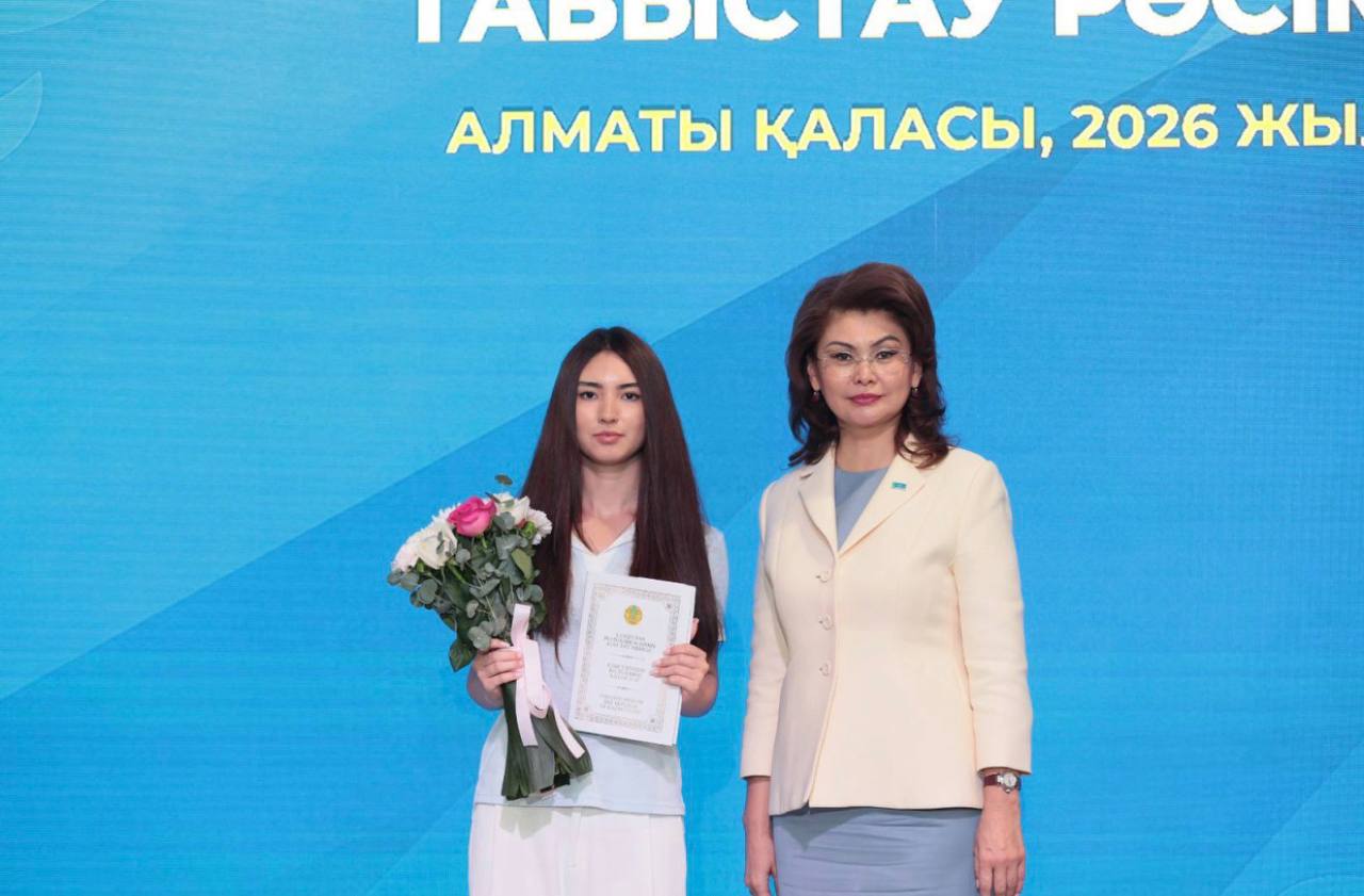 Narmina receiving a certificate of recognition with flowers at an official ceremony in Almaty